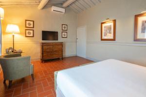 a bedroom with a bed and a desk and a television at Relais Villa Olmo - Place of Charme in Impruneta