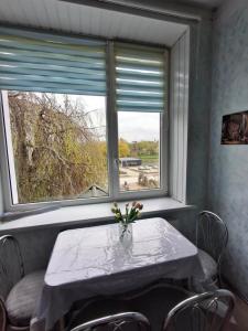 a table with a vase of flowers on it in front of two windows at Svečių namai miestelio centre in Mosėdis