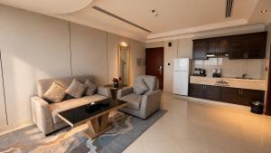 a living room with a couch and two chairs and a kitchen at Crown Tower Hotel in Al Jubail