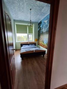 a bedroom with a bed and a painting on the wall at Svečių namai miestelio centre in Mosėdis