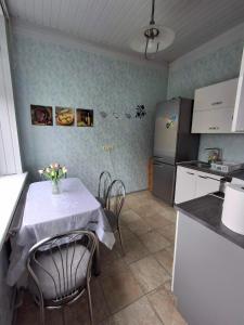 a kitchen with a table with chairs and a refrigerator at Svečių namai miestelio centre in Mosėdis