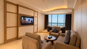 a living room with a couch and chairs and a tv at Crown Tower Hotel in Al Jubail