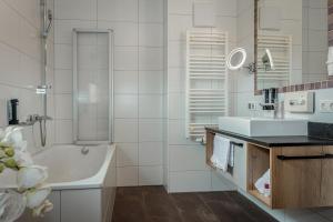 a white bathroom with a tub and a sink at Hotel Almrausch in Saalbach-Hinterglemm +36 photos