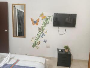 a bedroom with a tv and butterflies on the wall at Hotel Montserrat Luxury in Valledupar