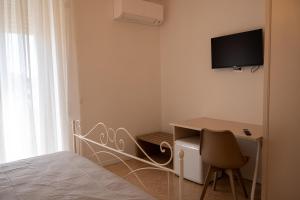a bedroom with a desk and a television on the wall at SanPatrizio Guest House in Torre San Patrizio