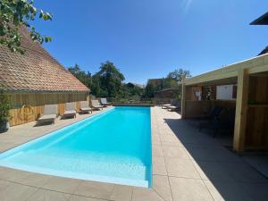 a swimming pool with lounge chairs next to a house at Gîte Du Balcon in Diebolsheim