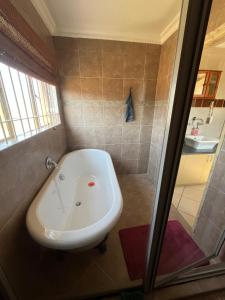 a bathroom with a bath tub and a sink at Diamo Guest House in Roodeplaat