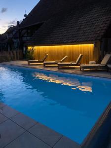 a swimming pool with chairs and lights on a fence at Gite Du Verger in Diebolsheim