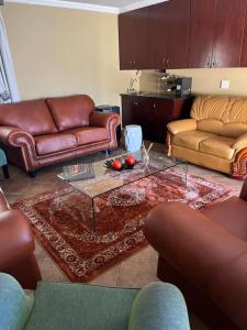 a living room with leather couches and a coffee table at Diamo Guest House in Roodeplaat