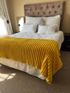 a large bed with a yellow blanket on it at Diamo Guest House in Roodeplaat