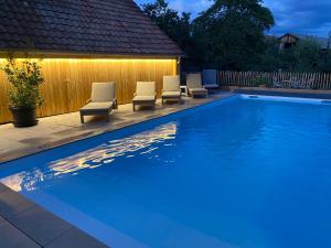 a swimming pool with chairs and lights on a fence at Gite du jardin in Diebolsheim