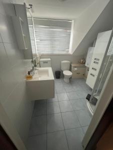 a white bathroom with a toilet and a sink at Maison Agathe in Brussels
