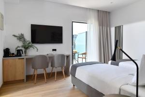 a hotel room with a bed and a desk and a television at Acropolis Lumina in Athens