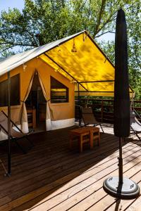 a yellow tent on a wooden deck with a table at Domaine Solio - Lodge isolée, nature, animaux in Satillieu