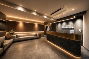 a lobby with couches and a sign on the wall at Hotel Arashi Nippombashi 2 No008 in Osaka