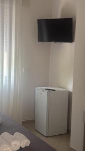 a tv on a wall above a small refrigerator at Stellarium House in Vibo Valentia