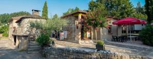 a stone building with a table and an umbrella at Camping Ushuaïa Villages Les Cruses in Ribes