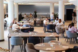 a group of people sitting at tables in a restaurant at Monumenti Heritage Hotel&Resort in Pula