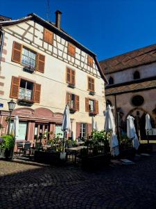 a building with umbrellas and tables in front of it at La Maison des Tanneurs in Ribeauvillé