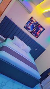 a bedroom with a blue bed with two pictures on the wall at Postive Vibes Hotel and Bar in Ikotun