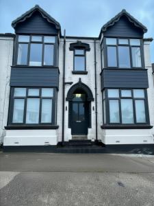 a white house with black windows and a door at The Mariner's Rest Aparthotel in Cleethorpes