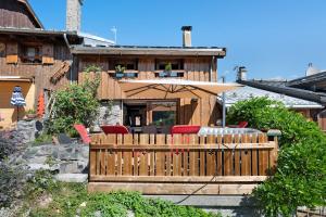 a wooden deck with red chairs and an umbrella at Chalet La Grange Courchevel in Courchevel