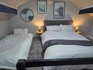 two beds in a bedroom with two lamps and mirrors at Cosy Colne Cottage in Colne