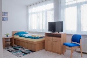 Schlafzimmer mit einem Bett, einem TV und einem Stuhl in der Unterkunft ŠD Urbánkova 2 in Košice