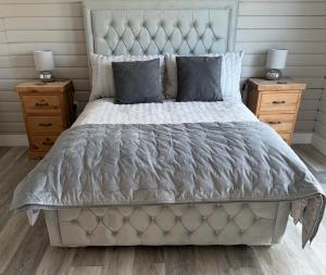 a bed with a gray comforter and two night stands at Danielle’s den in Doncaster