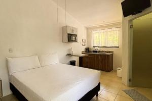a bedroom with a white bed and a kitchen at Club Voca 5 in Coco