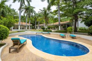 a swimming pool with blue chairs and palm trees at Club Voca 5 in Coco