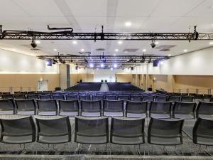 an empty auditorium with blue chairs and a stage at Novotel Paris Est Centre de Conférence in Bagnolet
