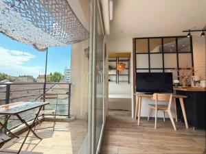 a room with a balcony with a table and a laptop at Balcon Vue Panoramique - Parking - Gare 200m in Vienne