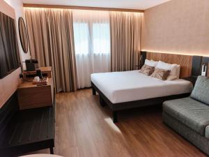 a hotel room with a bed and a couch at Novotel Montpellier in Montpellier