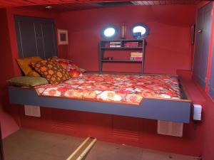 a small room with a bed in a red wall at Houseboat Zeldenrust in West Mersea