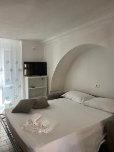 a bedroom with a white bed with a flat screen tv at Dimora Lieta in Pisticci