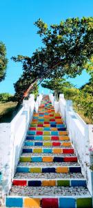 a staircase covered in colorful steps with trees above it at Pousada Roane - Taíba in Taíba +22 photos