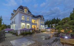 a large white house with purple umbrellas in front of it at Maro Luxury Boutique Villa - hotel in Da Thanh