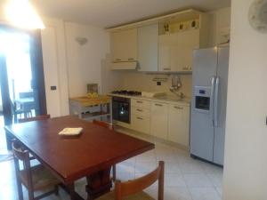 a kitchen with a wooden table and a refrigerator at CASA VACANZA Torre Lapillo PREMIUM in Torre Lapillo