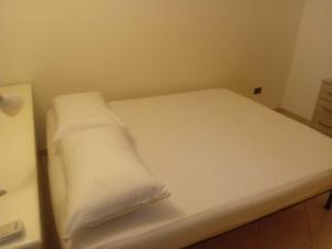 a white bed with two pillows on it in a room at CASA VACANZA Torre Lapillo PREMIUM in Torre Lapillo