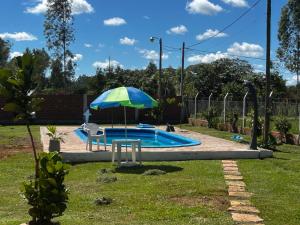 a pool with an umbrella and a chair and a table at Casa Verde in Mbocayaty
