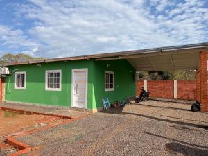 a green house with a white door and a building at Casa Verde in Mbocayaty