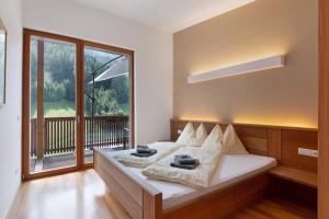 a bedroom with a bed and a large window at Pritscheshof Ferienwohnung Balkon in Malles Venosta