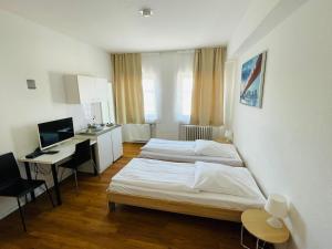 a room with two beds and a desk and a computer at Hotel Westend in Cologne