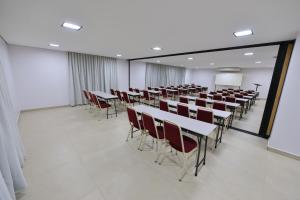 a room with rows of tables and chairs at Vinds Economic Hotel in Ipatinga