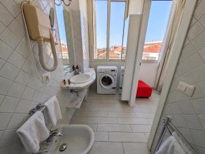 a bathroom with a sink and a washing machine at Attico al Centro in Cefalù +38 photos