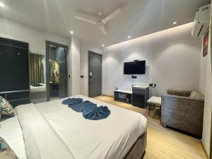 a bedroom with a bed and a couch and a television at Hotel Azul Ganga in Rishīkesh