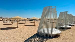 a group of metal chairs on a beach with umbrellas at U North Coast in Sidi Kirayr