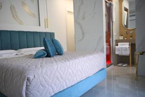 a bedroom with a bed with blue pillows at Kleos Luxury Rooms in Porto Empedocle