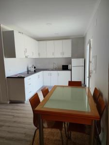 a kitchen with white cabinets and a wooden table and chairs at Casa do Valinho 